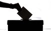 Schatten von einer Hand, die einen Zettel in eine Box steckt